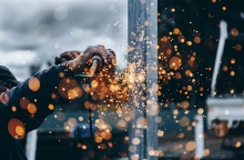 Χέρια εργαζόμενου στη βιομηχανία με εργαλείο που βγάζει σπίθες