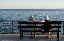 Ηλικιωμένοι κάθονται σε παγκάκι μπροστά στη θαλάσσα