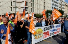 Άτομα που συμμετέχουν σε συγκέντρωση στο κέντρο της Αθήνας κρατώντας σημαίες και πανό της ΠΟΕ-ΟΤΑ