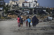 Παιδιά περπατούν δίπλα από βομβαρδισμένα κτίρια στη Γάζα