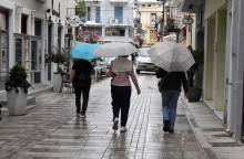 Άτομα κρατούν ομπρέλα ενώ περπατούν στον δρόμο