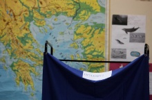 Παραβάν σε εκλογικό τμήμα με φόντο χάρτη της Ελλάδας
