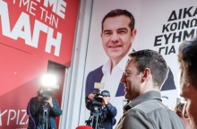 Ο Στέφανος Κασσελάκης προχωρά σε κτίριο που στο εξωτερικό του έχει αφίσα του ΑΛέξη Τσίπρα