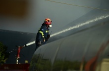 Πυροσβέστης δίπλα από μάνικα που ρίχνει νερό για την κατάσβεση φωτιάς