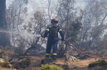 Πυροσβέστης με τη μάνικα ανά χείρας επιχειρεί για την κατάσβεσης φωτιάς