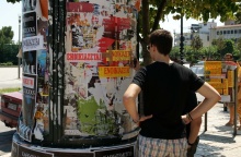 Ενοικιαστήρια σε κολώνα και νεαρό άτομο που κοιτά ενοικιαστήρια