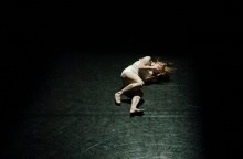 Γυναίκα σε εμβρυακή στάση σε σκοτεινό δωμάτιο με φως να πέφτει στο σώμα της