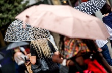 Άτομα προστατεύονται από τη βροχή με ομπρέλες