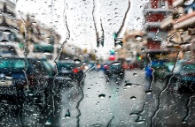 Σταγόνες βροχής σε τζάμι αυτοκινήτου όπου φαίνονται τα προστινά οχήματα