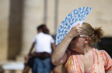 Γυναίκα κρατά στο κεφάλι της την βεντάλια της για να προφυλαχτεί από τον ήλιο