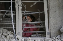 Παιδάκι πίσω από ερείπια σπιτιού στη Γάζα κοιτά τον φωτογραφικό φακό