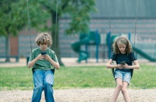 Παιδιά σε κούνια κοιτούν το κινητό τους