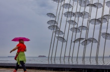 Γυναίκα κρατά ομπρέλα ενώ περπατά στην παραλία της Θεσσαλονίκης