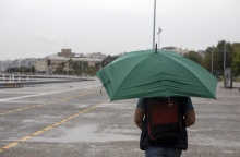 Άτομο προστατεύεται με ομπρέλα από καταιγίδα