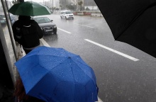 Άτομο με ομπρέλα περιμένουν εν μέσω βροχής σε στάση λεωφορείου 