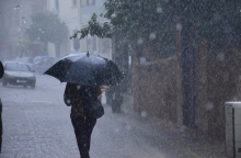 Γυναίκα προστατεύεται με ομπρέλα εν μέσω καταιγίδας