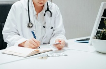 Γιατρός διαβάζει πληροφορίες σε φάρμακα και τις καταγράφει σε σημειωματάριο
