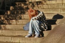 Κορίτσι καθισμένο σε σκαλιά, έχει κρύψει το κεφάλι της στα γόνατά της