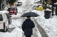 Άτομο περπατά με ομπρέλα μέσα στα χιόνια