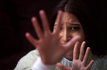 Γυναίκα με τρόμο στα μάτια προτάσσει τα χέρια της για να αντικρούσει επίθεση