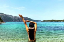 Γυναίκα τεντώνεται και απολαμβάνει τις διακοπές της με θέα τη θάλασσα