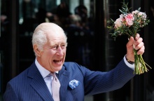 Ο Βασιλιάς Κάρολος χαμογελά κρατώντας ένα μπουκέτο λουλούδια