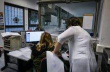 Γυναίκα σε υπολογιστή στην υπηρεσία της και από πάνω της μία άλλη γυναίκα που της δίνει οδηγίες