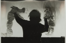 Θέατρο Σκιών και άτομο πίσω από το πανί με φιγούρες στα χέρια