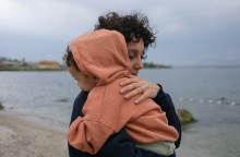 Μητέρα με παιδί αγκαλιά στην ακρογυαλιά