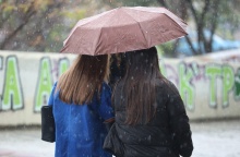 Γυναίκες προστατεύονται από τη βροχή κάτω από ομπρέλα