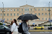 Πολίτες με ομπρέλα προστατεύονται από τη βροχή στο κέντρο της Αθήνας