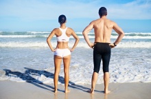 Γυναίκα και άνδρας με γυρισμένη την πλάτη στον φακό σε παραλία 