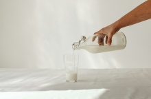 Ποτήρι με γάλα και μπουκάλι με γάλα σε λευκό φόντο