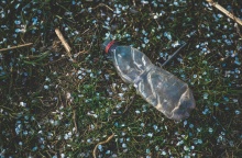 Πλαστικό μπουκάλι πάνω σε χώμα με φυτά