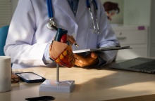 Γιατρός που σημειώνει έχοντας στο γραφείο του ένα ομοίωμα καρδιάς