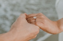 Χέρι άνδρα κρατά χέρι γυναίκας με δαχτυλίδι, εικόνα που μας δείχνει ότι έγινε πρόταση γάμου