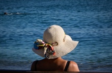 Γυναίκα με καπέλο κάθεται σε παγκάκι εν μέσω καύσωνα