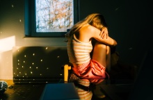 Γυναίκα κρύβει το πρόσωπό της και έχει στάσει σώματος αντίθετη από τον φωτογραφικό φακό