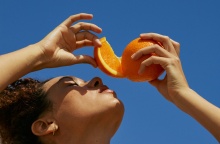 Κοπέλα στον ήλιο με κομμένο πορτοκάλι πάνω από το πρόσωπό της