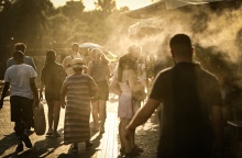 Πολίτες περπατούν υπό υψηλές θερμοκρασίες δίπλα σε σύστημα που βράζει σταγόνες νερού για δροσιά