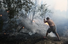 Άτομο επιχειρεί με κλαδί για την κατάσβεση φωτιάς