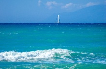 Κυματάκια σε παραλία και στο βάθος ένα ιστιοφόρο