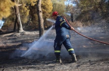 Πυροσβέστης με τη μάνικα ανά χείρας επιχειρεί για την κατάσβεσης φωτιάς