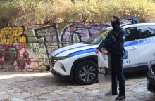 Αστυνομικός με την εξάρτισή του δίπλα από περιπολικό