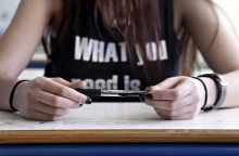 Μαθήτρια κρατά στυλό ενώ κάθεται στο θρανίο της