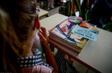 Μαθήτρια κάθεται στη θέση της έχοντας τα βιβλία της μπροστά της πάνω στο θρανίο και σημειώματα για καλή σχολική χρονιά