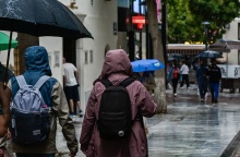 Πολίτες με ομπρέλες προστατεύονται από τη βροχή