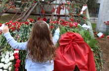 Παιδί αφήνει ένα κόκκινο γαρύφαλλο στο μνημείο για την εξέγρεση του Πολυτεχνείου