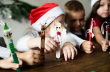 Παιδιά με χριστουγεννιάτικα σκουφιά κρατούν χριστουγεννιάτικα στολίδια