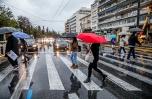 Άτομο περπατούν υπό βροχή χρησιμοποιώντας ομπρέλες